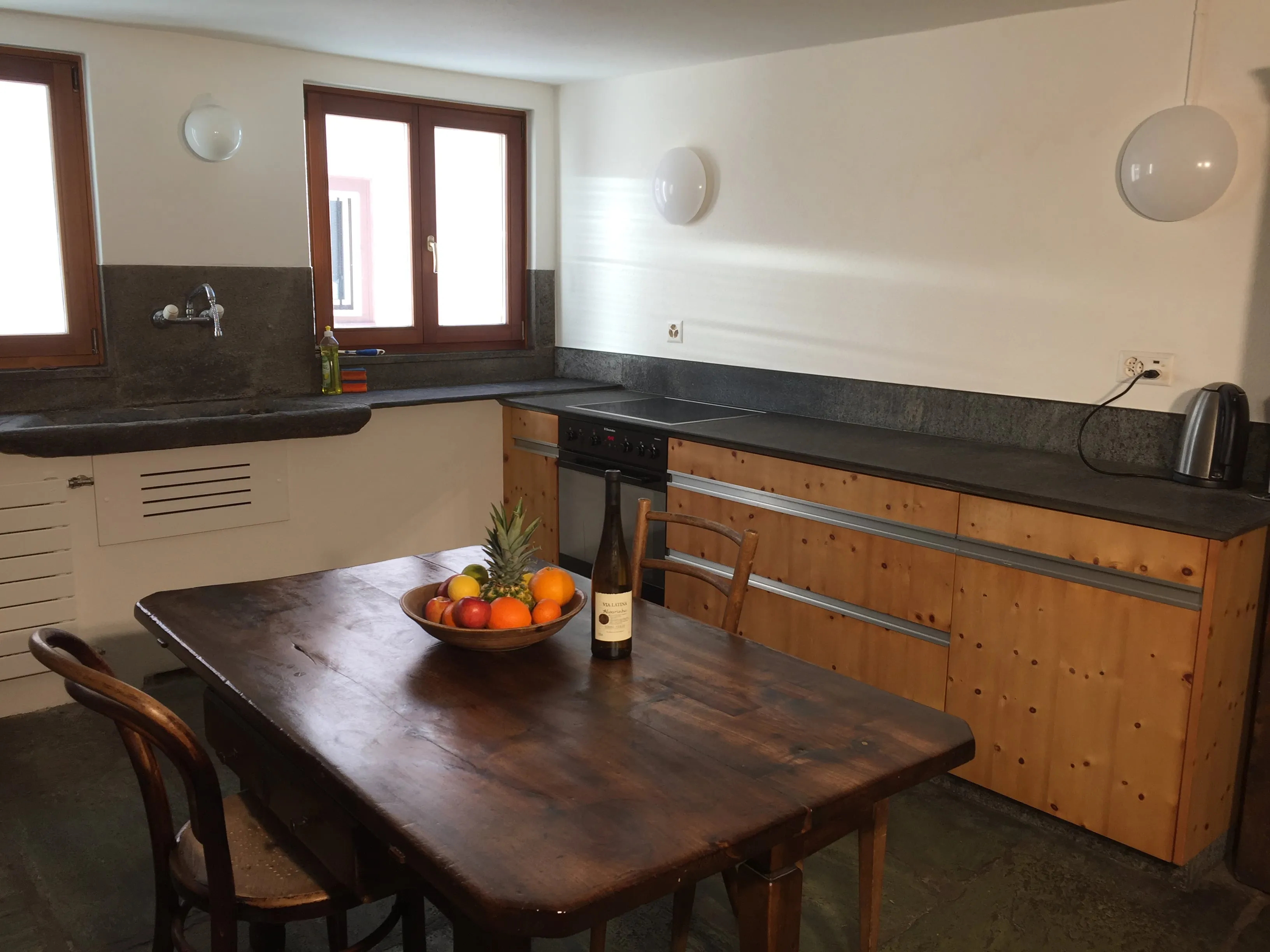 Ausgestattete Küche mit modernen Geräten und Steinboden